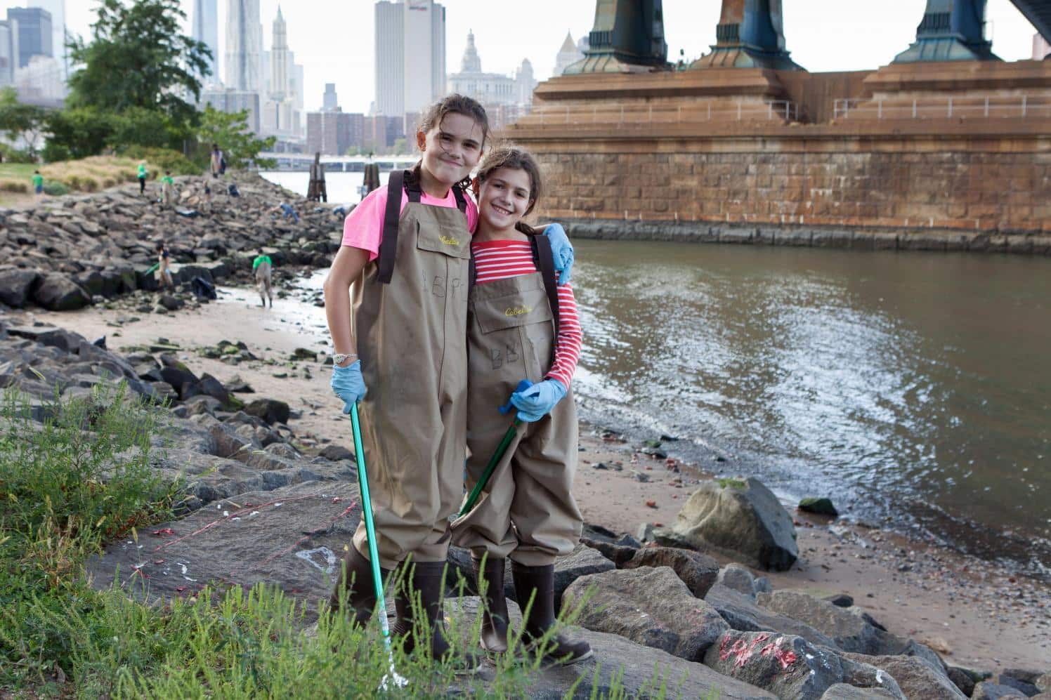 Two girls posing in waders by the water underneath the Manhattan Bridge.