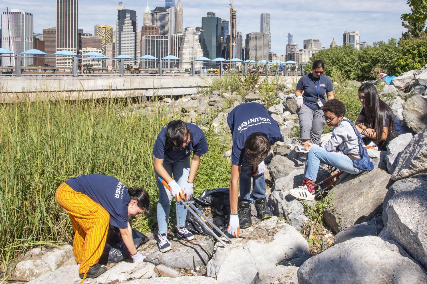 Fall 2018 TIDES Volunteers pick up trash along the piers on a sunny day.