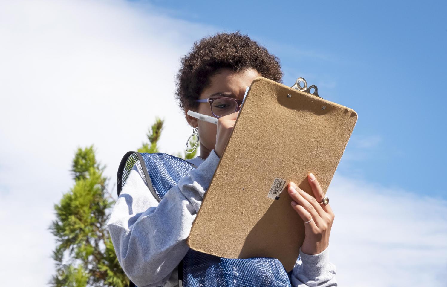 Volunteer writing on a clipboard on a sunny day.