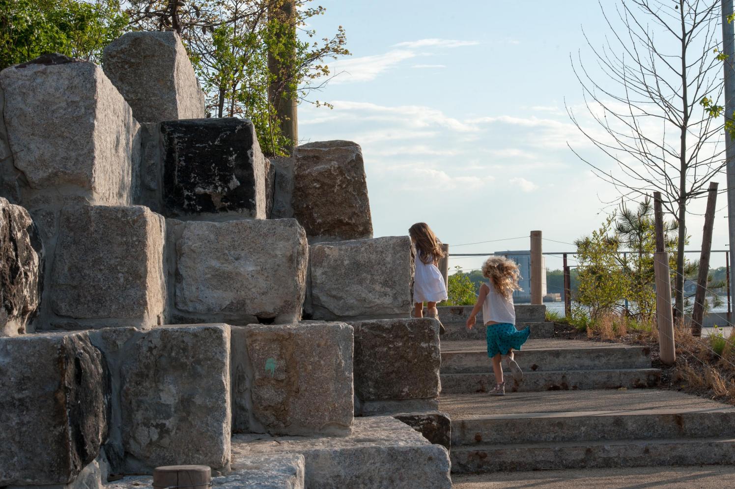 Two small children running up steps next to granite blocks.