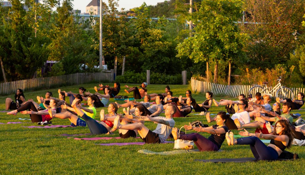 People on yoga mats doing sit ups at sunset.