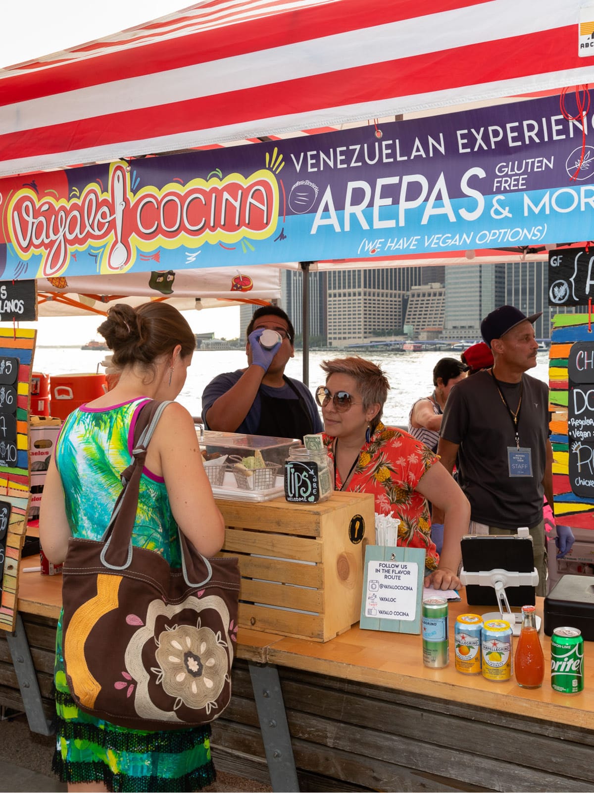 Woman in line at a colorful arepa stall.