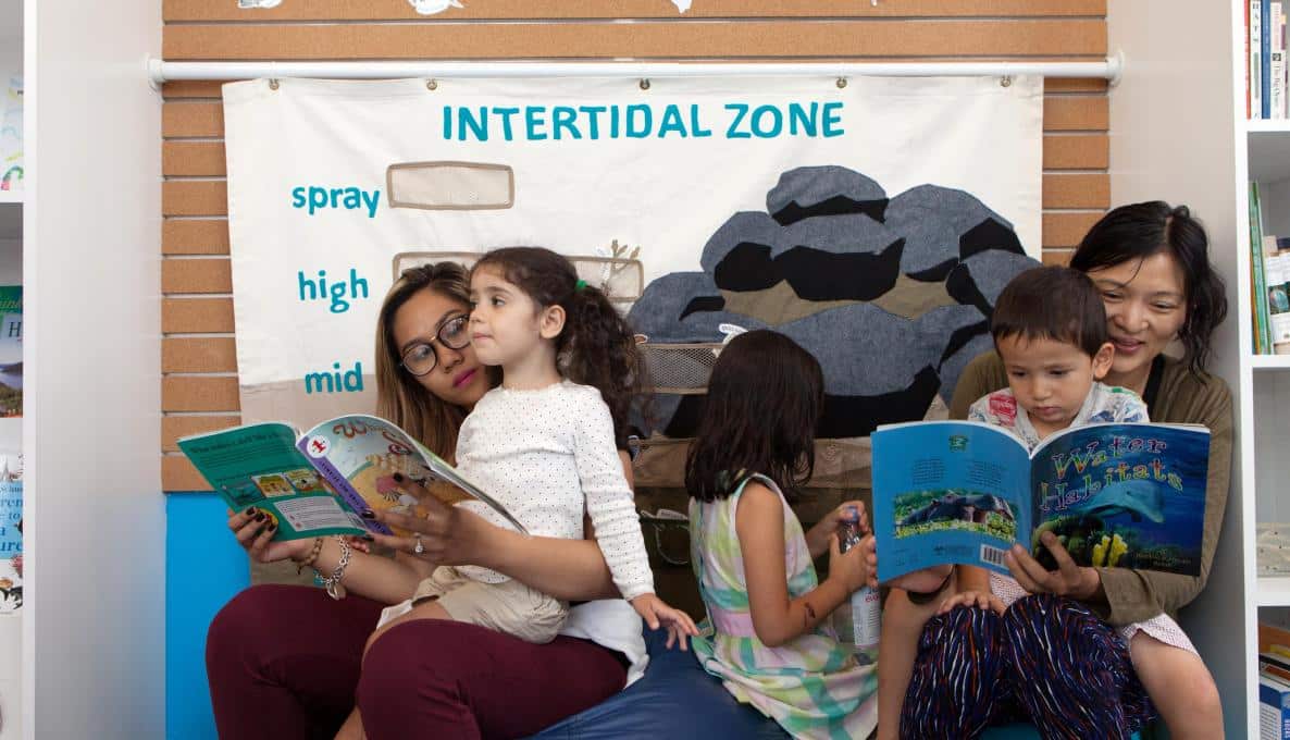 Families reading books in a classroom.