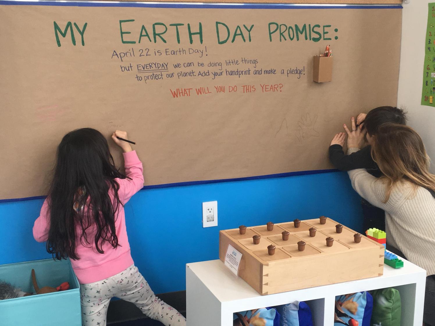 Children writing on an Earth Day poster.